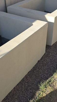 two cement planters sitting next to each other on the side of a building with grass