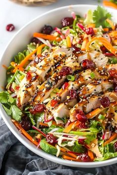 a salad with chicken and cranberries in a white bowl