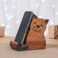 a wooden cat phone holder with a cellphone in it's mouth on a table