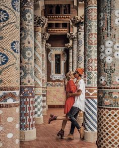 a man and woman walking through an ornately decorated building with columns in the foreground