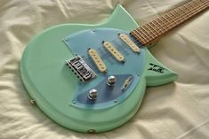 a blue and green guitar laying on top of a white sheet