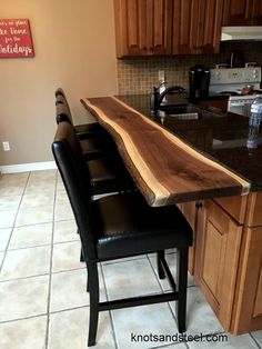 a kitchen counter made out of wood and black leather chairs