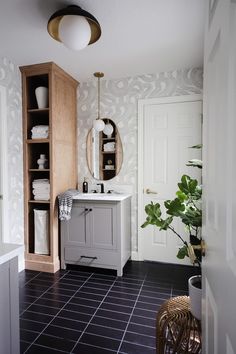 a bathroom with black tile flooring and white walls, along with a wooden cabinet