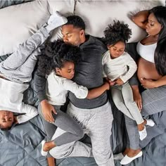 a group of people laying on top of a bed with their arms around each other