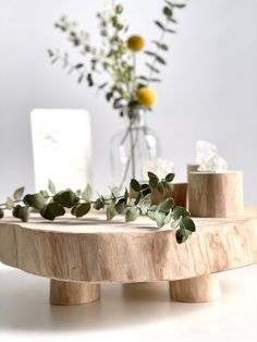 a wooden table topped with a vase filled with flowers and greenery on top of it