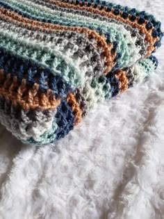 two crocheted blankets sitting on top of a white bed covered in fluffy fur