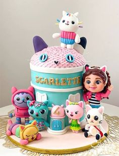 there is a birthday cake with many toys on the top and bottom tier, as well as an image of a doll