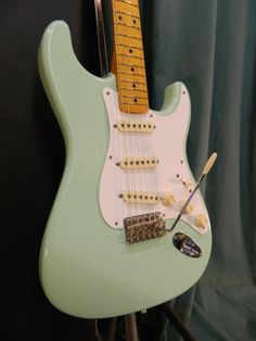 a green electric guitar sitting on top of a stand