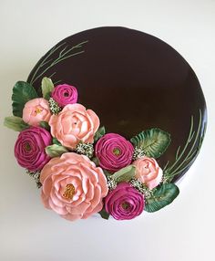 a chocolate cake decorated with pink flowers and greenery