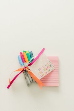 several pens and notepads tied together on a white surface