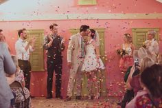 a bride and groom kiss as confetti falls from the ceiling in front of them