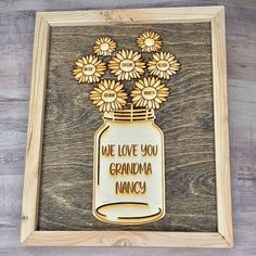 a wooden sign with flowers in a mason jar that says, we love you grandma nancy