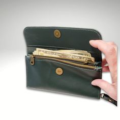 a hand holding a wallet with money sticking out of the front and side pockets on both sides