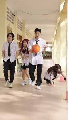 three people are walking down the hallway with a basketball in their hand and one man is holding a ball