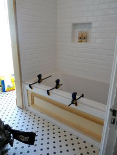 a bathroom with black and white tile flooring and a bathtub in the middle