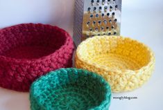 three crocheted bowls sitting next to a grater