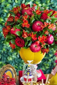 a vase filled with red flowers sitting on top of a table next to other items