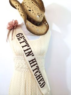 a woman's white dress with a hat and sash around her neck that says get well dressed