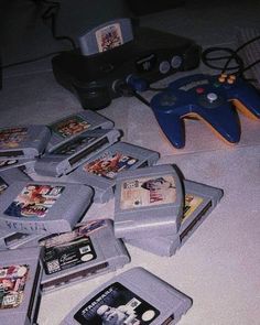 a pile of video games sitting on top of a white floor next to a game controller