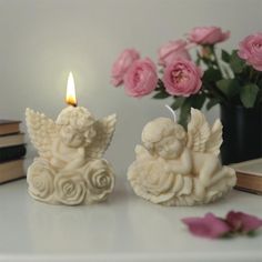 two candles with angel figurines sitting next to each other