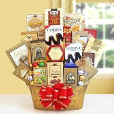 a gift basket filled with assorted chocolates and candies, wrapped in red ribbon