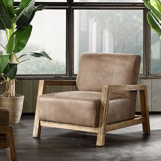 a brown chair sitting in front of a window next to a potted plant on top of a hard wood floor