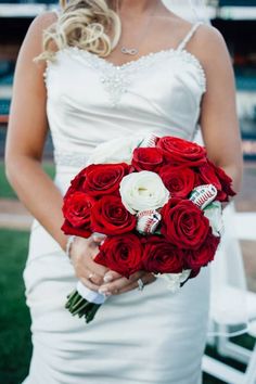 a bride holding a bouquet of red and white roses