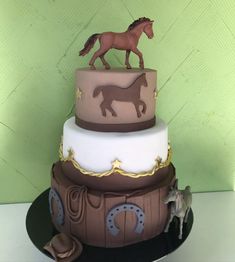 a three tiered cake with a horse figurine on top and other decorations