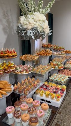 an assortment of pastries and desserts on display at a buffet table with flowers in the background