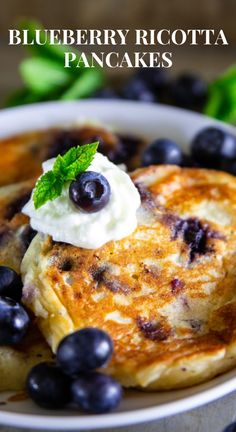 blueberry pancakes on a plate with whipped cream and fresh blueberries in the background