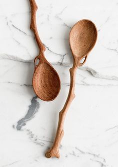 two wooden spoons sitting on top of a white marble counter next to each other