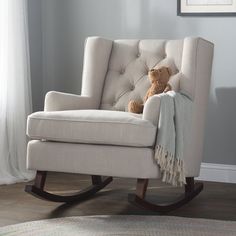 a teddy bear sitting in a rocking chair with a blanket on it's back