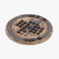 an old, rusty metal object with lots of black stones on the top and bottom