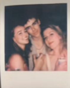 two women and one man are taking a selfie in front of a polaroid