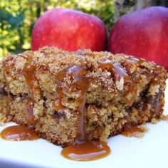 a close up of a piece of cake on a plate with apples in the background