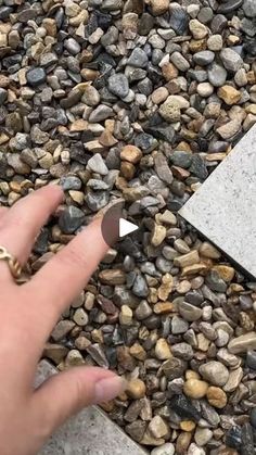 a person's hand pointing at a rock and stone area with rocks on it