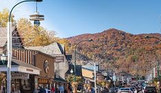 people are walking down the street in front of shops and stores with mountains in the background