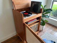 an old record player is sitting on top of a wooden cabinet next to a potted plant