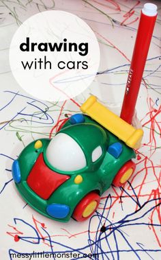 a green toy car sitting on top of a table next to a red pencil and marker