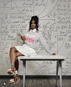 a woman sitting on top of a white table next to a wall covered in writing