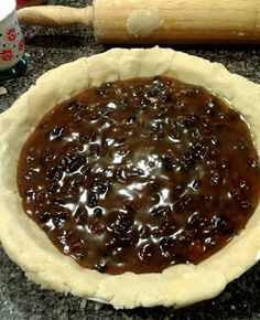 an uncooked pie crust with chocolate sauce in it on a kitchen counter next to a rolling pin