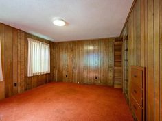 an empty room with wood paneling and red carpet