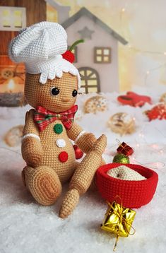 a crocheted gingerbread man sitting next to a christmas ornament and candy bowl