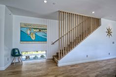 an empty living room with stairs leading up to the second floor and a painting on the wall