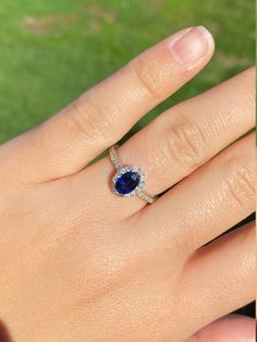 a woman's hand with a diamond and blue sapphire ring on her left hand