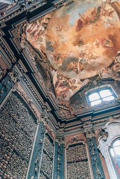 an ornate ceiling with paintings on it and two windows in the center is lit by sunlight