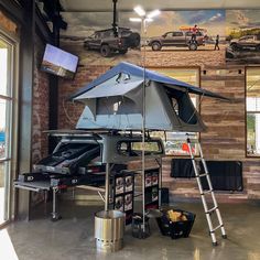 a large tent set up in the middle of a room with cars on the wall