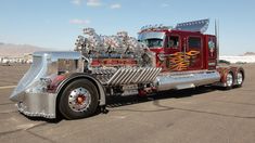 a red semi truck with chrome paint on it's flatbed is parked in a parking lot