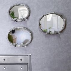 three mirrors on the wall above a dresser