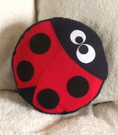 a red and black ladybug pillow sitting on top of a white blanket